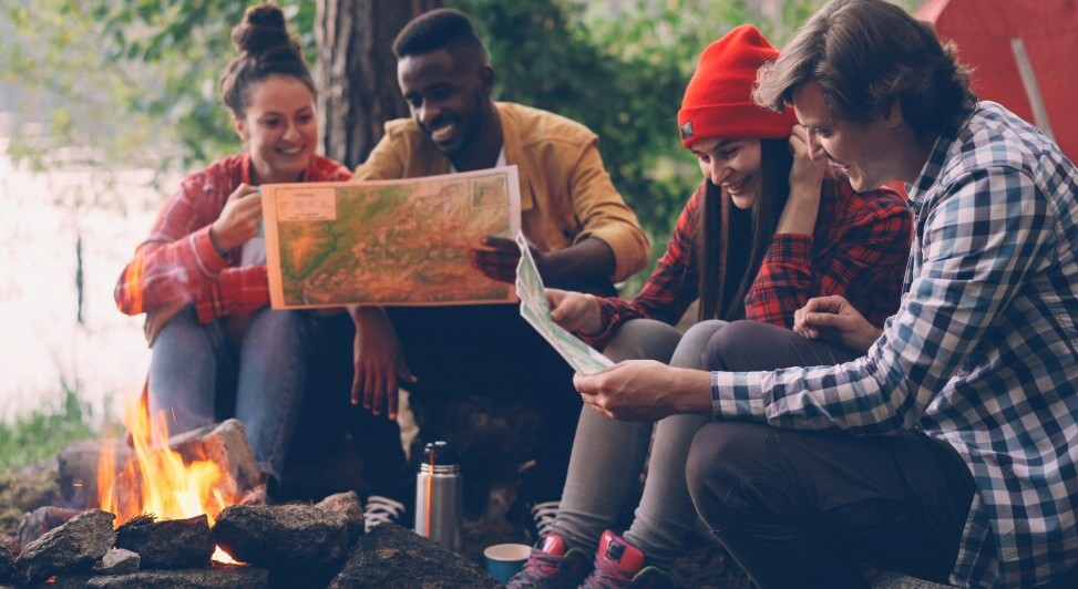 people looking at maps around a fire